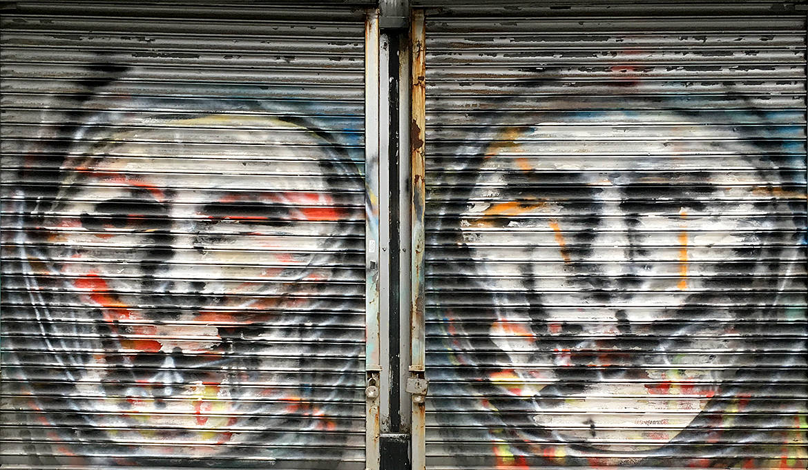 two faces painted on security fence outside a store