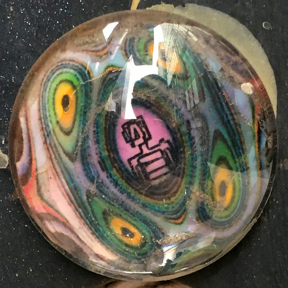 A round cabochon with a printed back stuck to the side of a girder