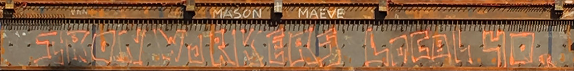 Close up photo of a large iron beam with orange spray painted graffiti saying "Iron Workers Local 40" in a stylized font