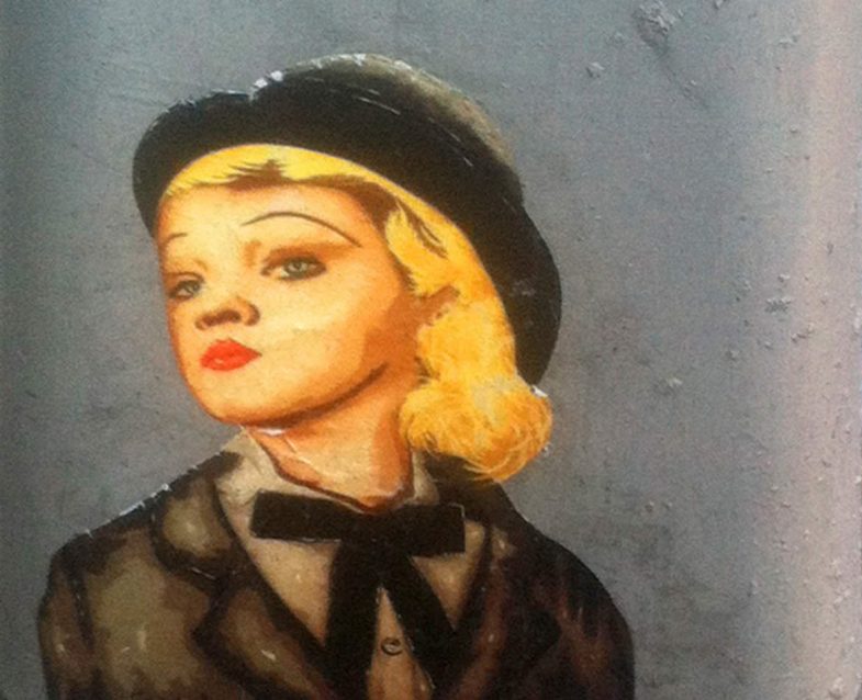 A glamorous paste up graphic of a blonde woman wearing a bowler hat and old style tuxedo