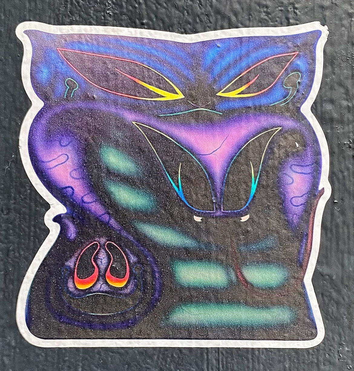 Die cut sticker of an illustrated fantasy science fiction cat with a white border stuck on a black pillar.