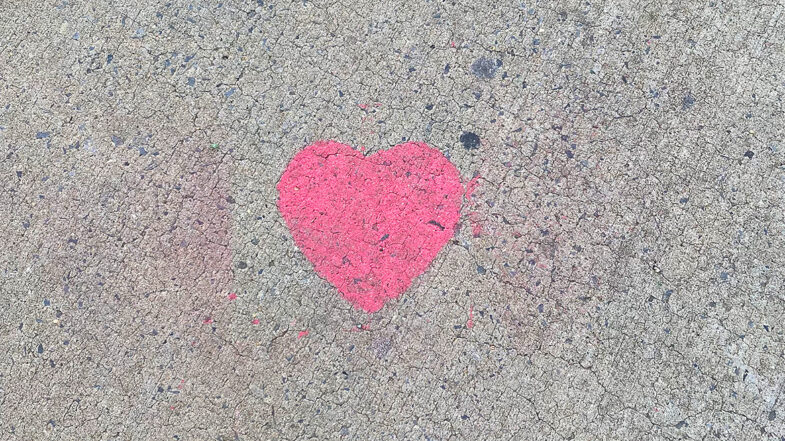 A spray painted pink heart on the sidewalk