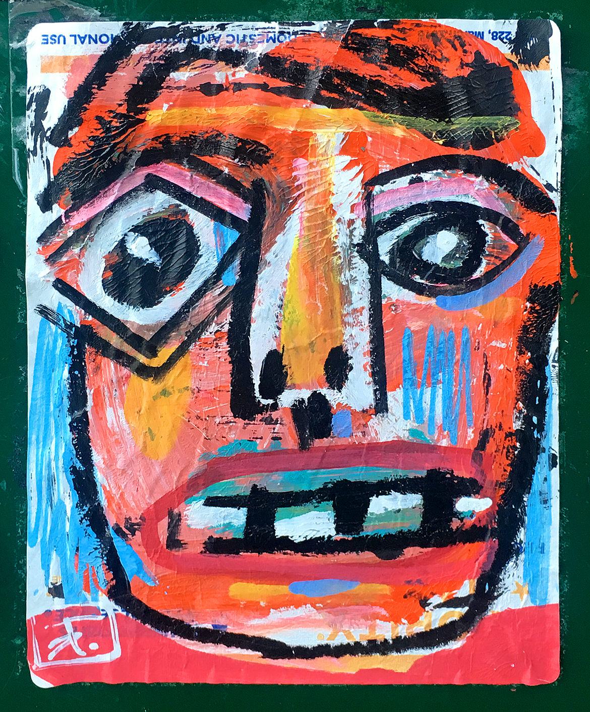 a colorful painted wide eyed face on a postal address label sticker