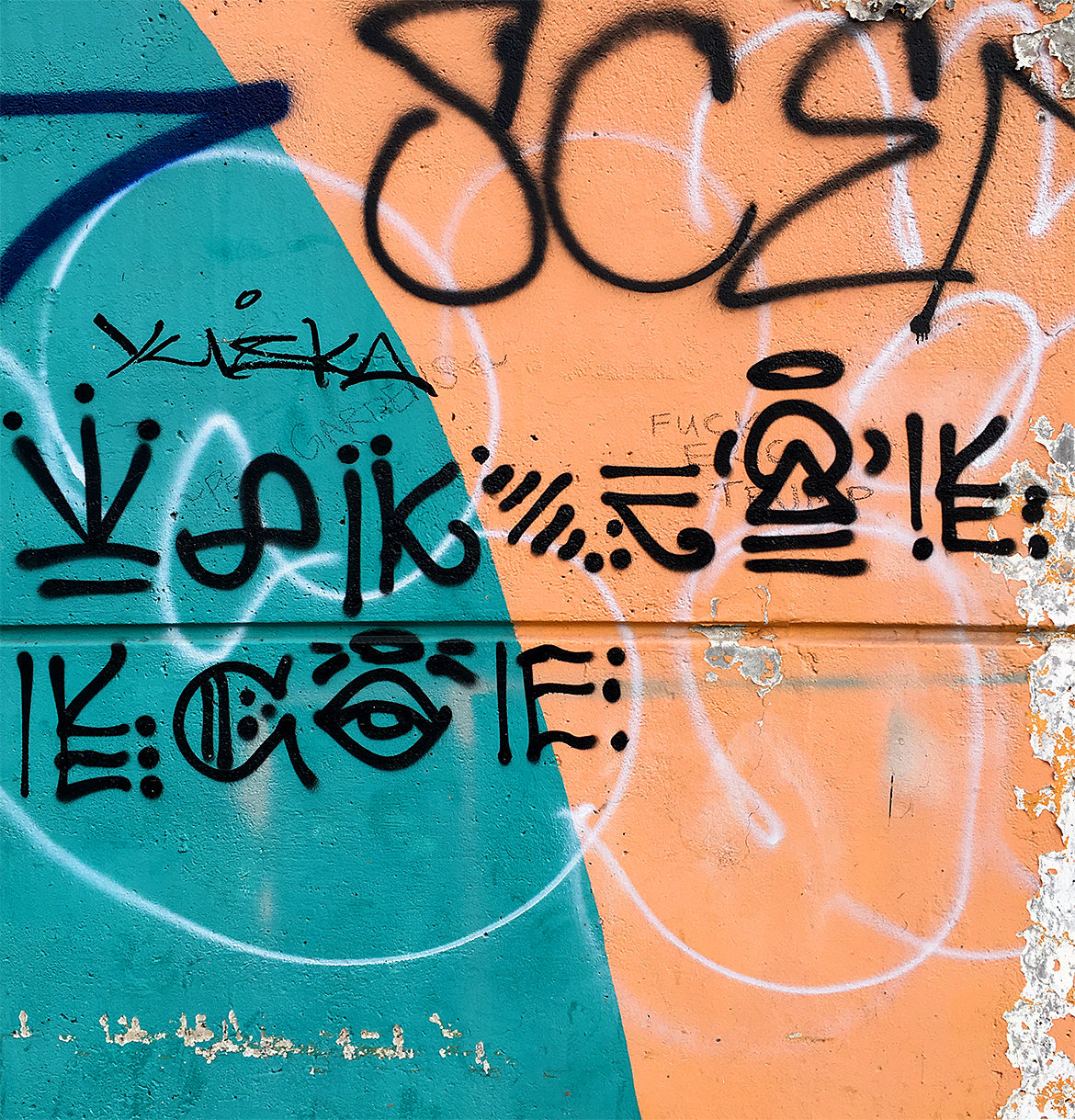 teal and orange wall with spray paint hieroglyphics