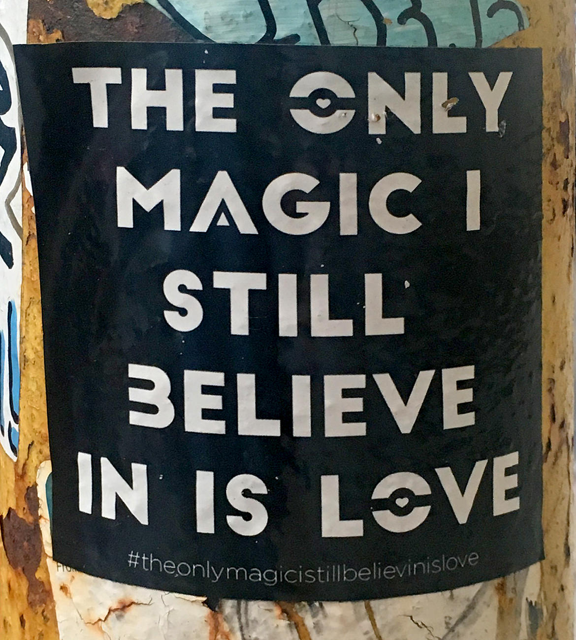 black sticker with white text saying, "the only magic I still believe in is love"