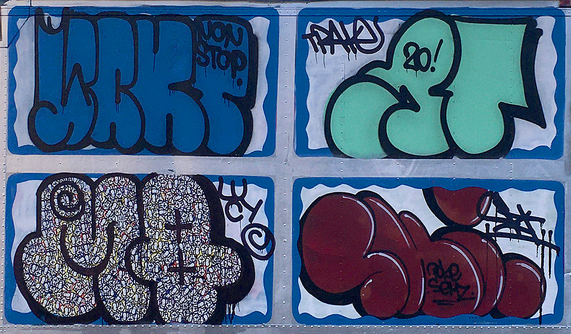 Four pack of spray paint graffiti lettering pieces on the side of a truck