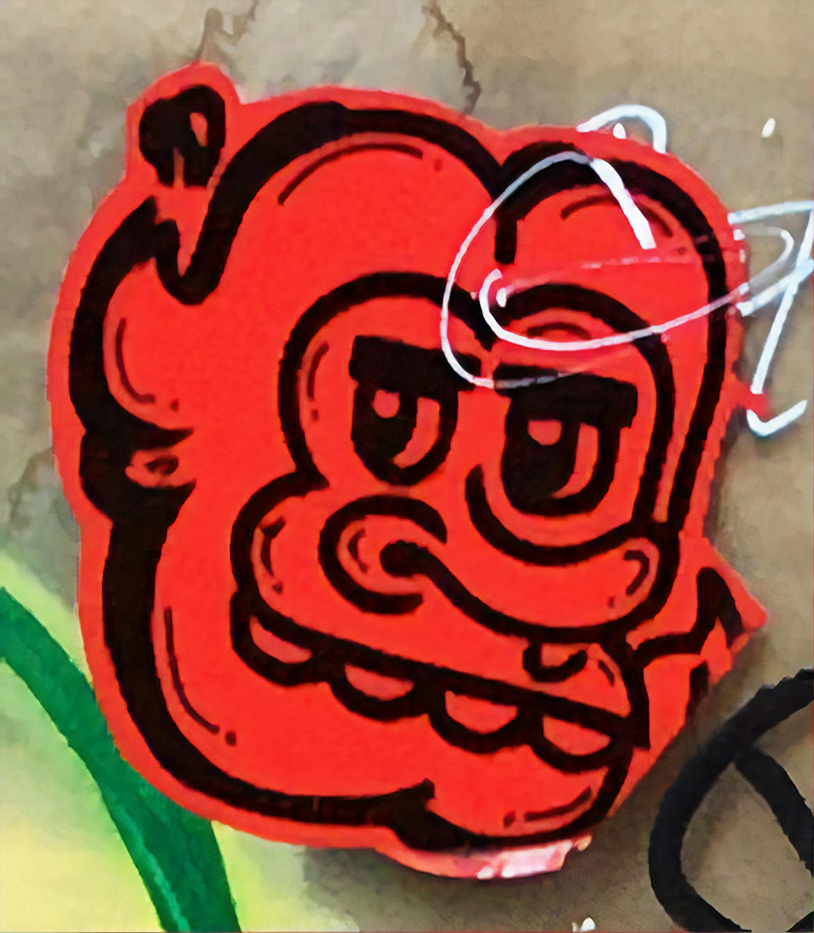 A graffiti sticker of a cartoon face in red and black